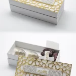 White rectangular gift box topped with a gold star-lattice frame, featuring Arabic coffee cups and premium dates inside