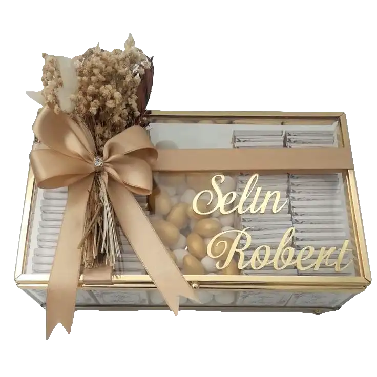 A transparent rectangular gift box with gold accents and the names ‘Selin Robert’ on the lid, tied with a matching ribbon