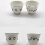 Two porcelain Arabic coffee cups featuring delicate floral and geometric motifs, displayed side by side