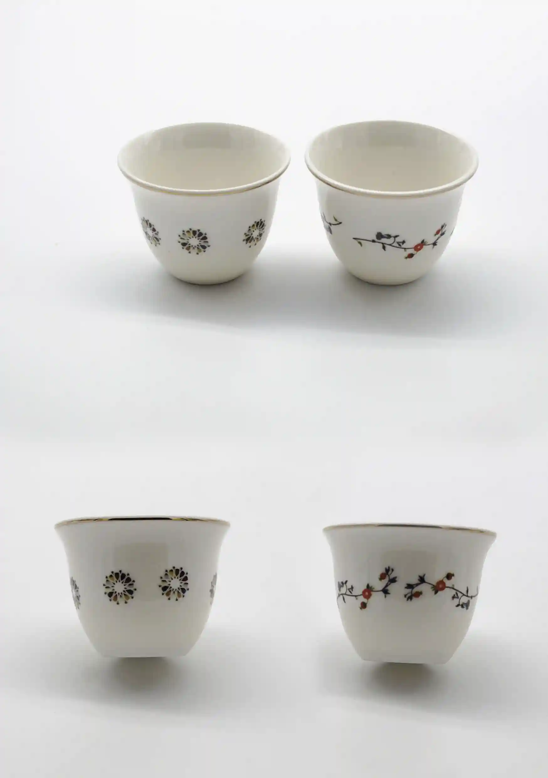 Two porcelain Arabic coffee cups featuring delicate floral and geometric motifs, displayed side by side