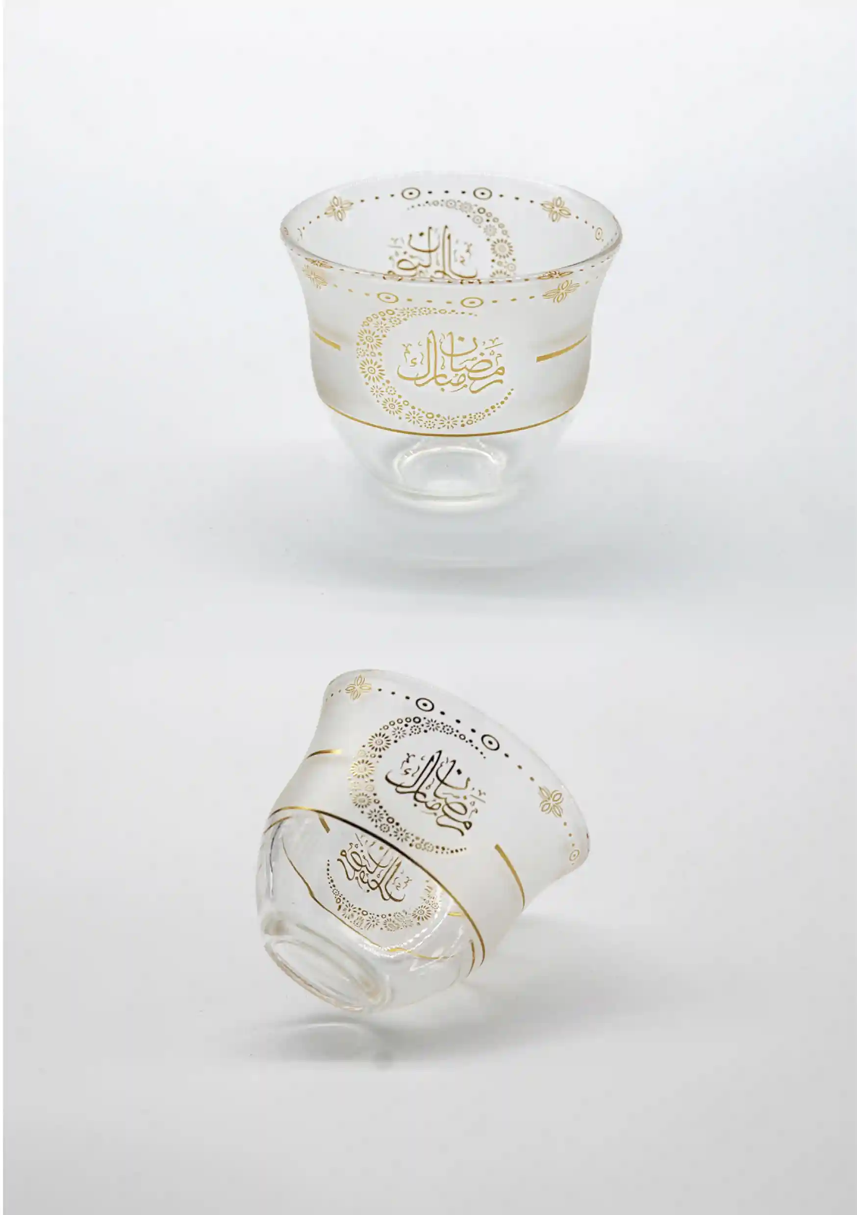 Frosted glass cups adorned with gold Arabic calligraphy and ornate designs for Ramadan celebrations
