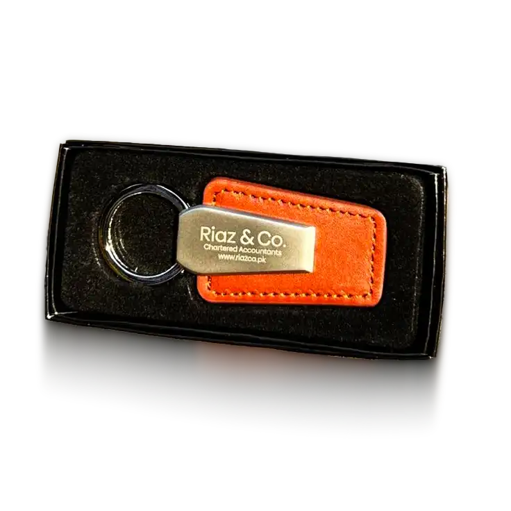 luxury-leather-metal-keychain A brown and metal keychain inscribed with ‘Riaz & Co.’ presented in a black gift box Gifts for CEOs in the UAE