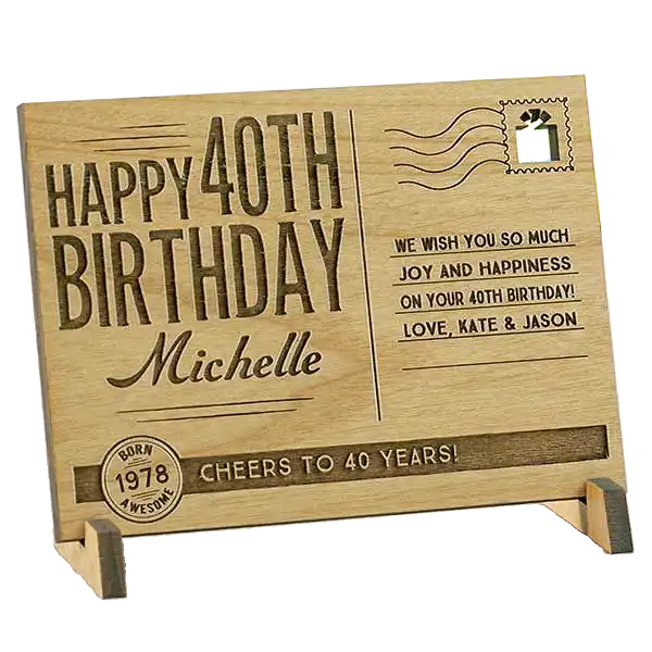 A wooden postcard-style birthday card engraved with ‘Happy 40th Birthday Michelle’ and a personalized message, displayed on a small stand. Birthday Gifts in the UAE