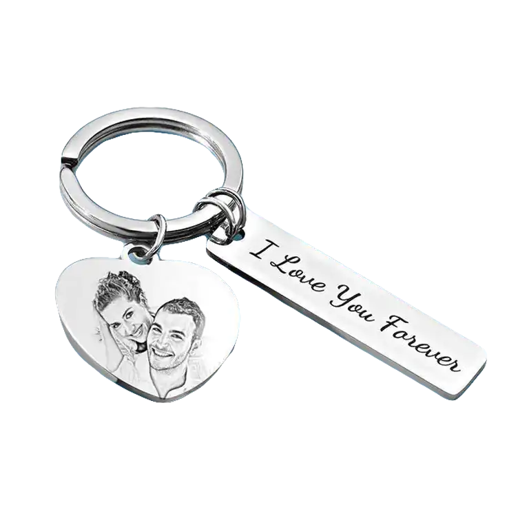 A silver keychain with a heart-shaped charm engraved with a couple’s picture and a rectangular tag reading ‘I Love You Forever.'