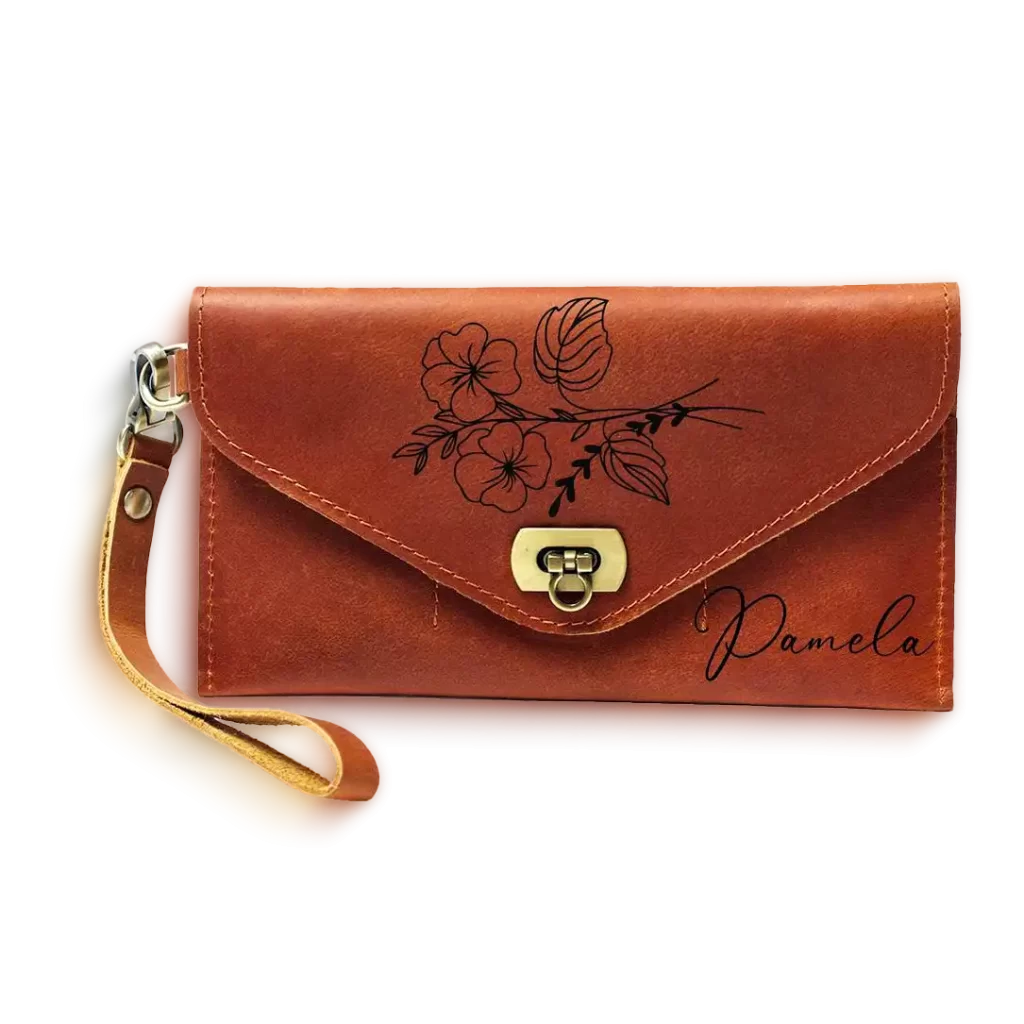 A brown leather clutch wristlet engraved with floral artwork and the name Pamela on the front
