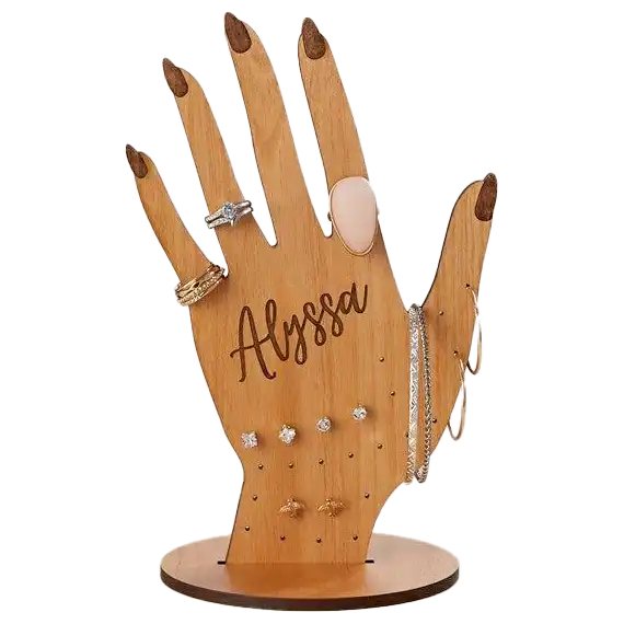 A hand-shaped wooden jewelry holder engraved with the name Alyssa, displaying rings, earrings, and bracelets