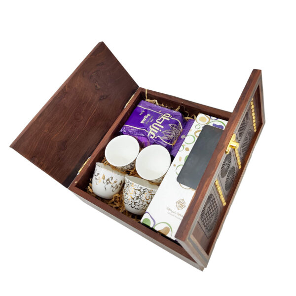 Traditional wooden door gift box open to reveal Arabic calligraphy qahwa cups, dates, and Arabic coffee.