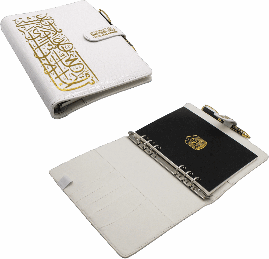A5 white PU leather binder with gold Arabic calligraphy and the UAE emblem, featuring a 6-ring binding, notebook, and pen for UAE National Day Gifts 2025.