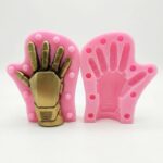Pink two-part silicone mold displaying a gold-painted robotic armor hand model inside.