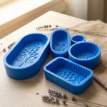 Collection of blue food-grade silicone molds with floral and grape cavity designs on a wooden surface.