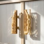 A pair of long, rectangular door handles made of clear casting resin encapsulating natural burl wood on a white cabinet.