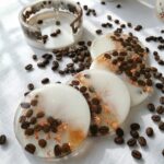 Clear epoxy resin coasters and a matching holder encapsulating real coffee beans and copper flakes.
