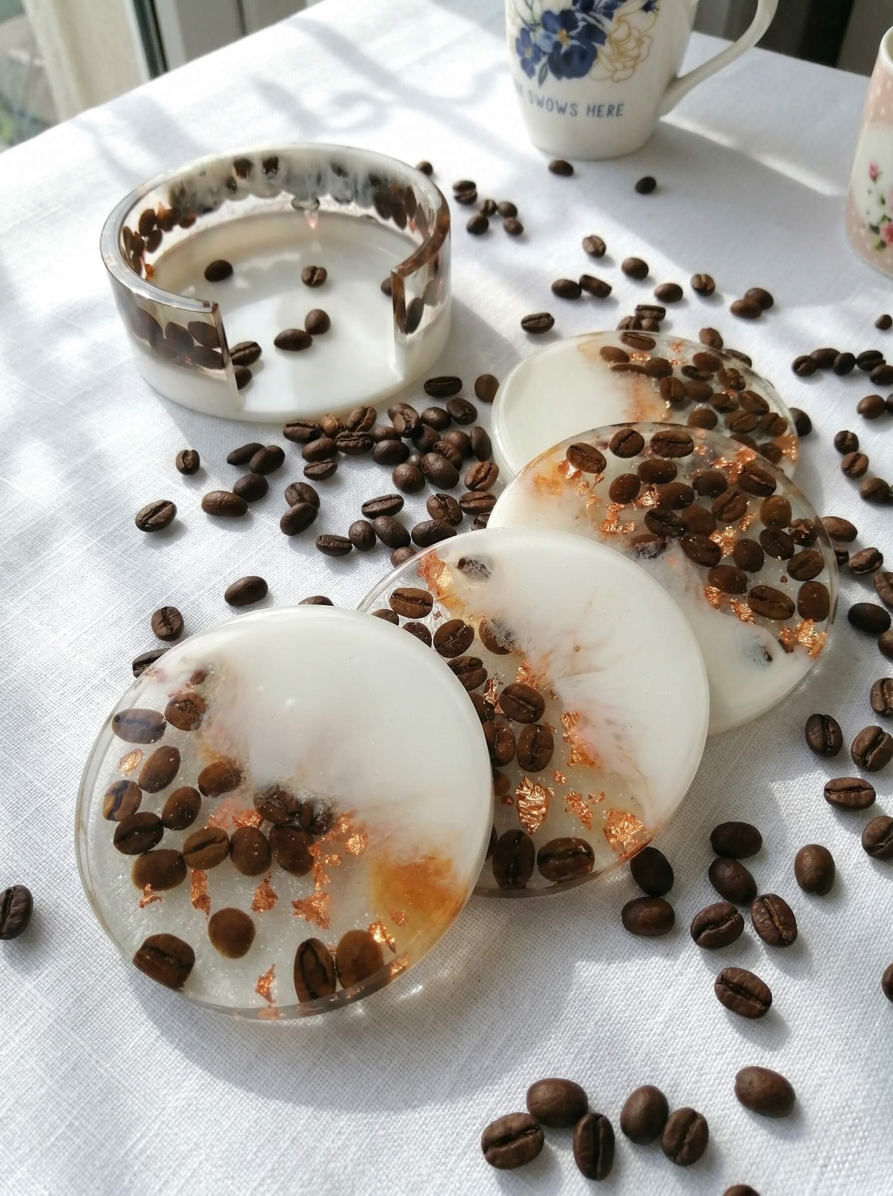 Clear epoxy resin coasters and a matching holder encapsulating real coffee beans and copper flakes.