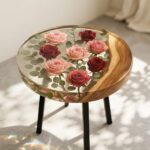 Round wooden side table featuring clear epoxy resin encapsulation of pink and red roses with green leaves.