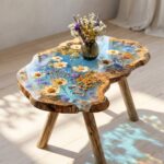 Small irregular shaped live-edge wood side table featuring clear epoxy resin encapsulation of yellow and blue daisies.