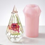 Faceted clear epoxy resin ring holder encapsulating a single preserved rose next to a pink silicone mold.