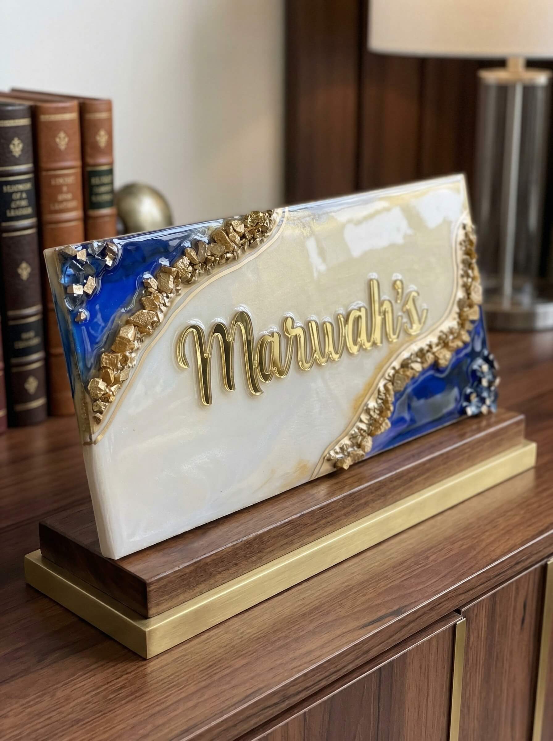 Freestanding geode style custom colored epoxy resin nameplate in pearlescent white and deep blue with crushed gold texture and raised gold lettering on a wooden base.