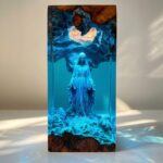 Custom blue epoxy resin diorama encapsulating a miniature statue inside a glowing wooden grotto.