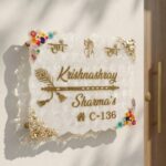 Custom white textured epoxy resin house address plate with gold lettering, encapsulated colorful flowers, and gold flakes mounted on an exterior wall.